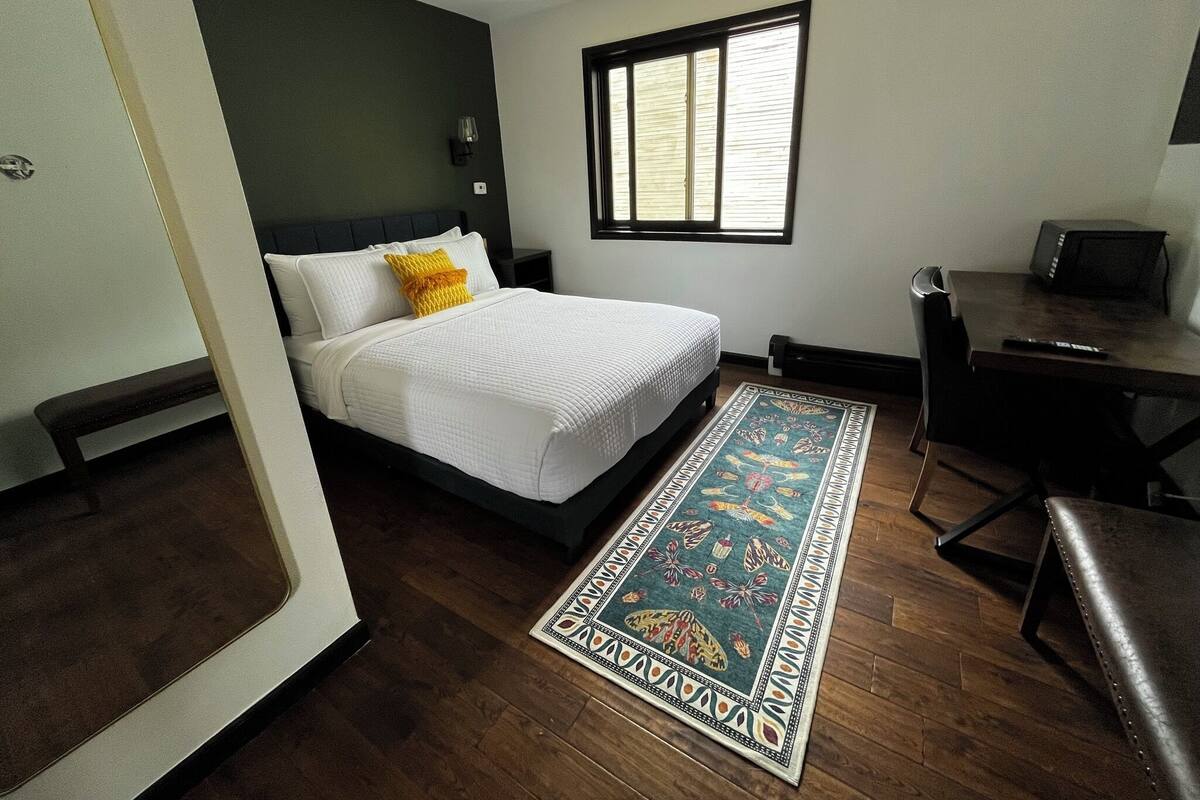 A modern hotel room with a bed, a desk, and a window.