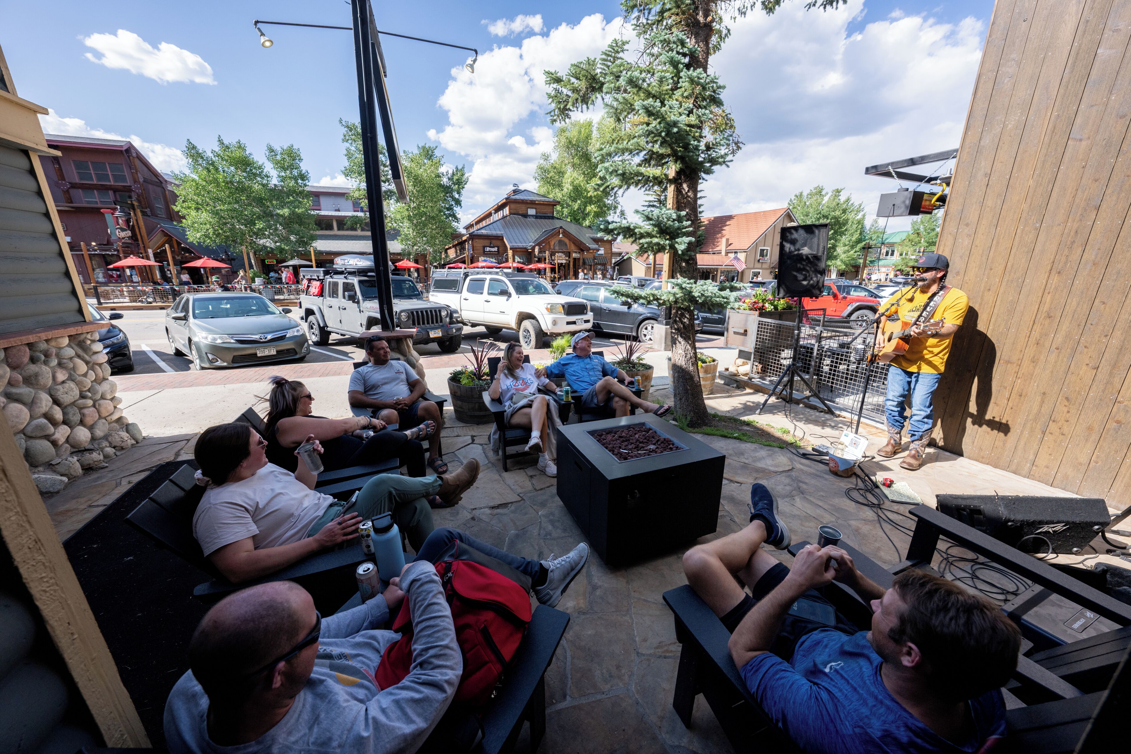 An outdoor seating area with stone walls, a fire pit, and a stage for live music.