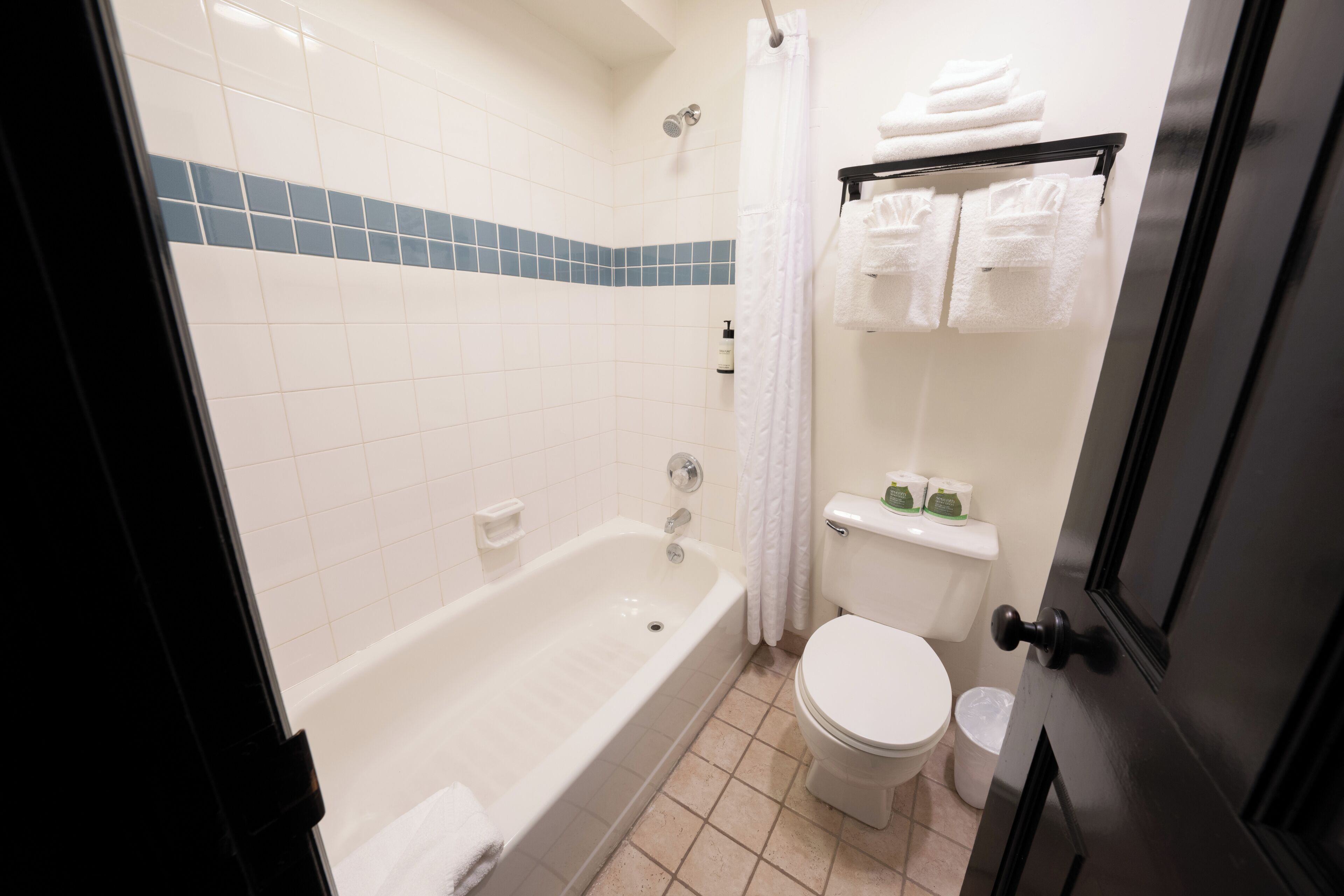 A bathroom with a bathtub, toilet, and a towel rack.