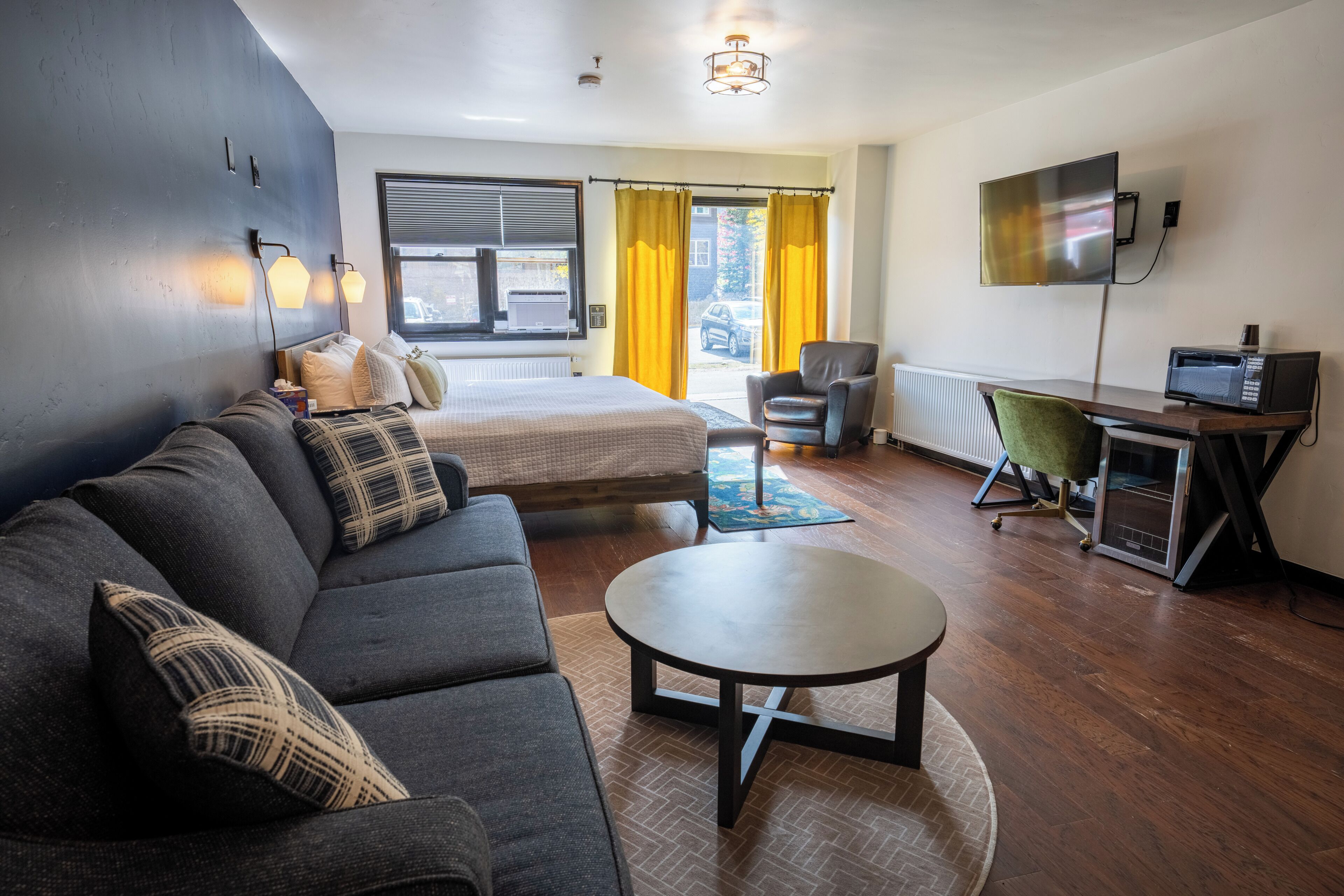 Habitación de hotel moderna con sofá, cama, escritorio con computadora y televisión.