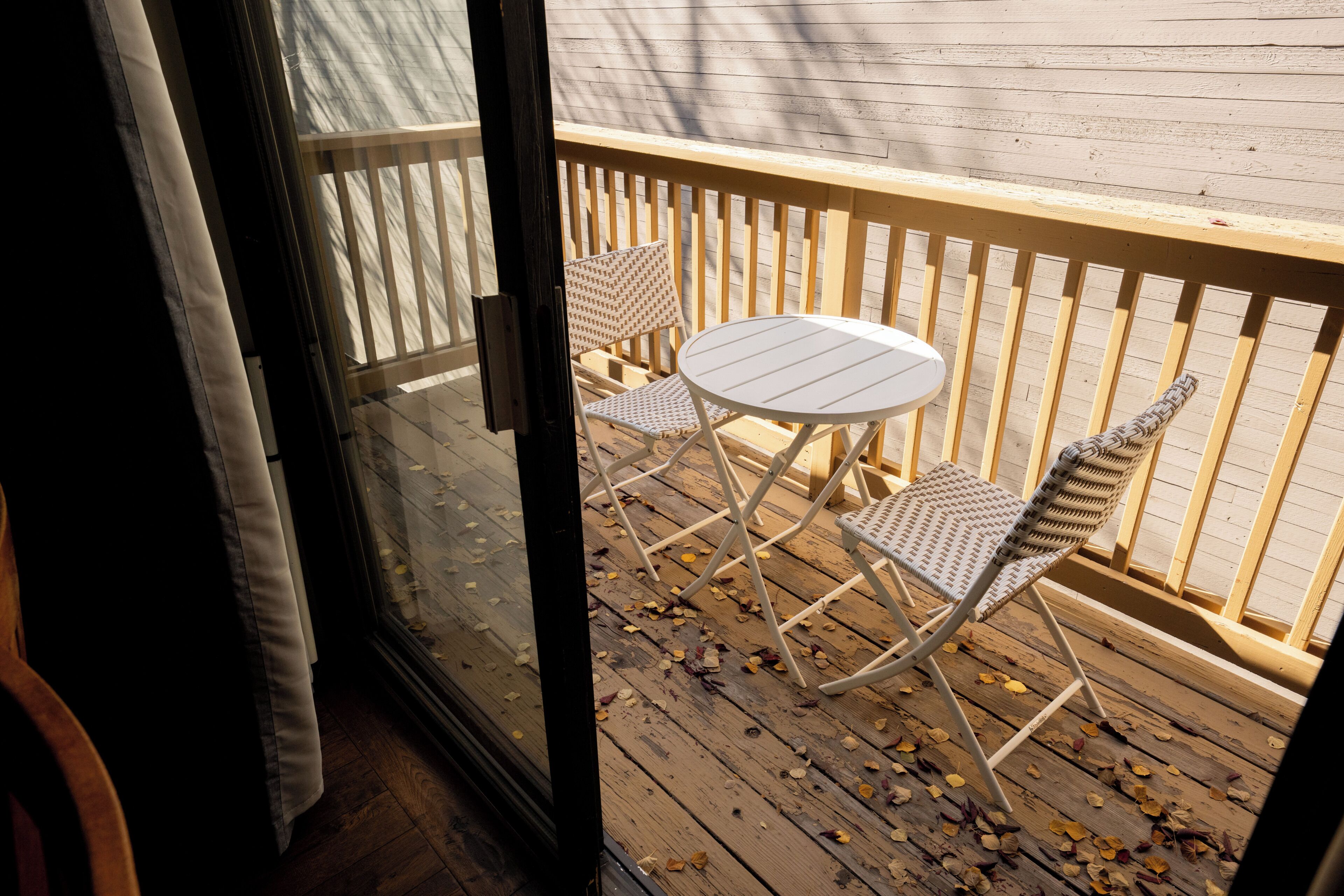 Une terrasse en bois avec une table blanche et deux chaises en osier.