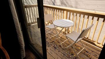 Une terrasse en bois avec une table blanche et deux chaises en osier.