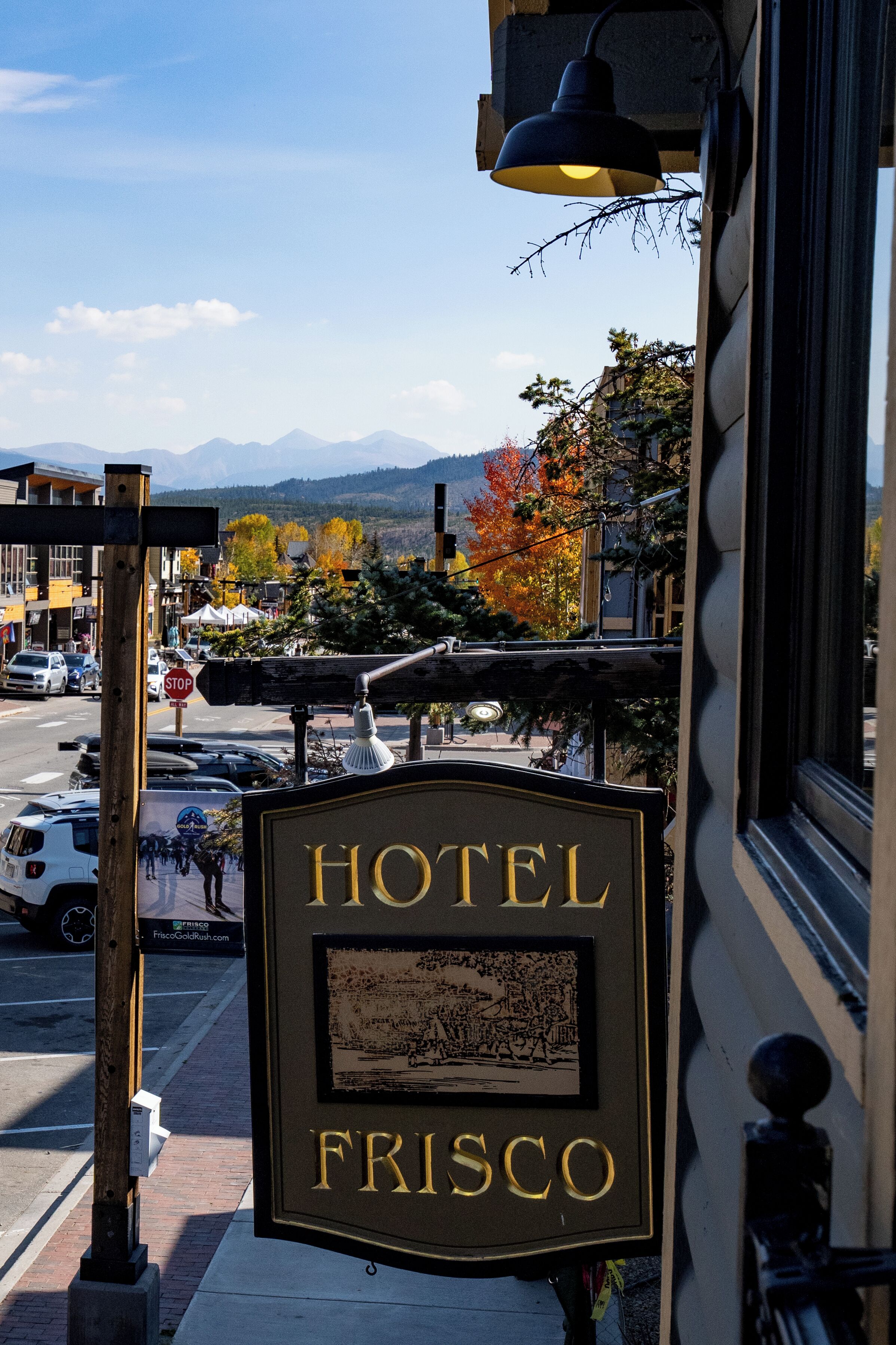 Un letrero de hotel con el nombre 'HOTEL FRISCO' y una vista de la calle y las montañas al fondo.