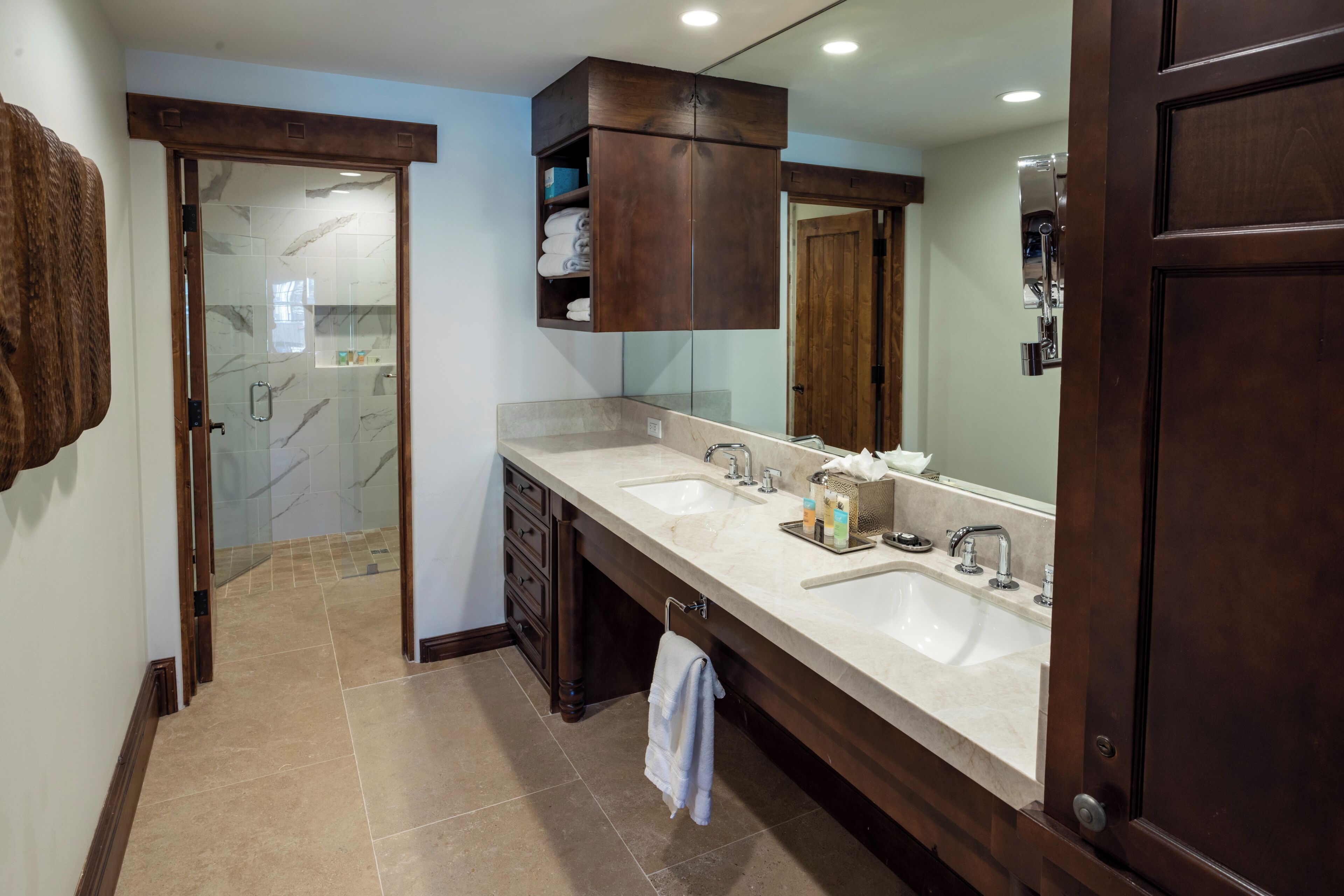 Un baño moderno con lavamanos doble, un espejo grande y un mueble de tocador de madera.