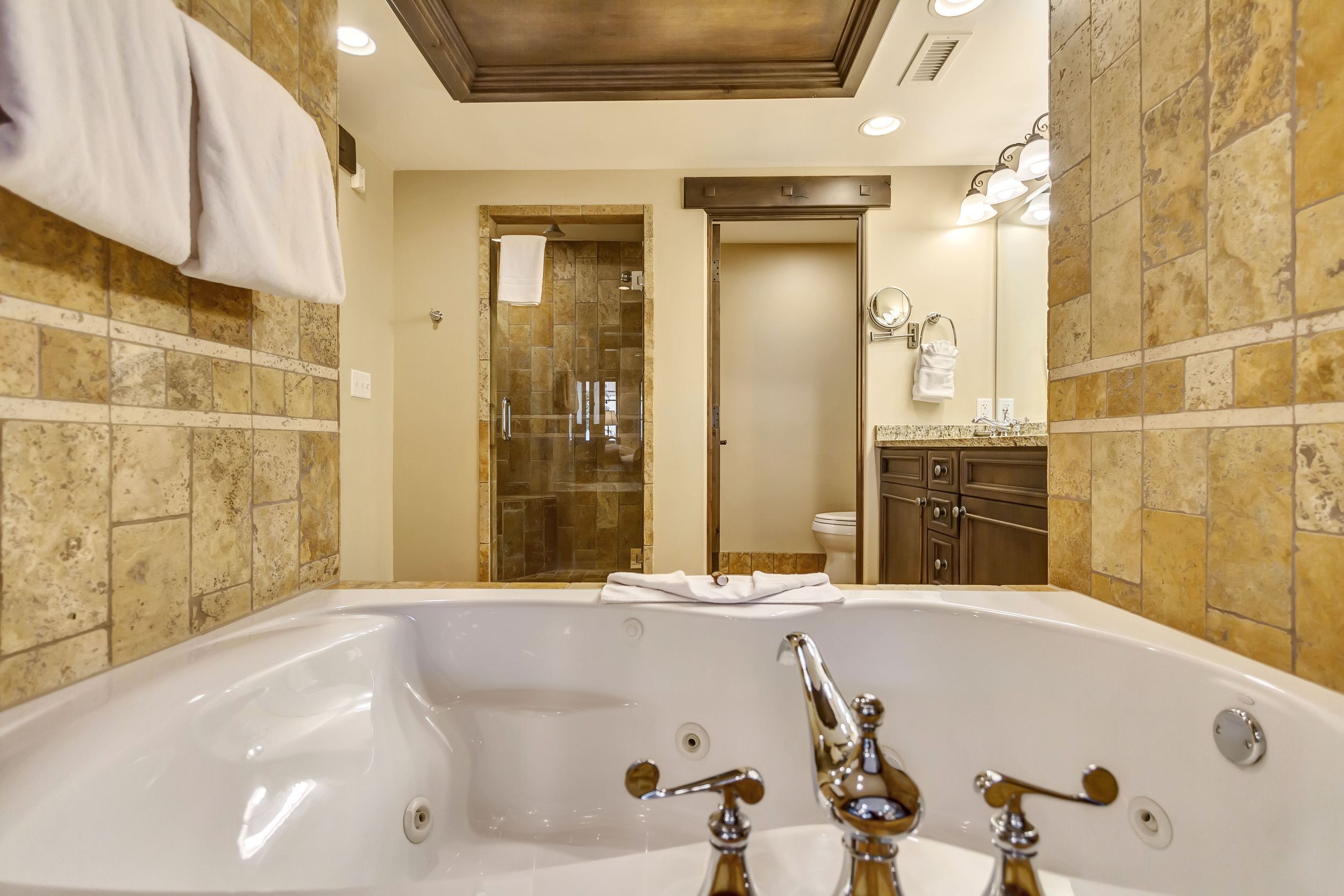 A modern bathroom with a large bathtub, a glass-enclosed shower, and a vanity with a mirror and towel rack.