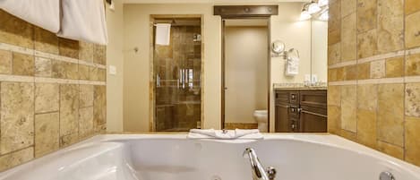 A modern bathroom with a large bathtub, a glass-enclosed shower, and a vanity with a mirror and towel rack.