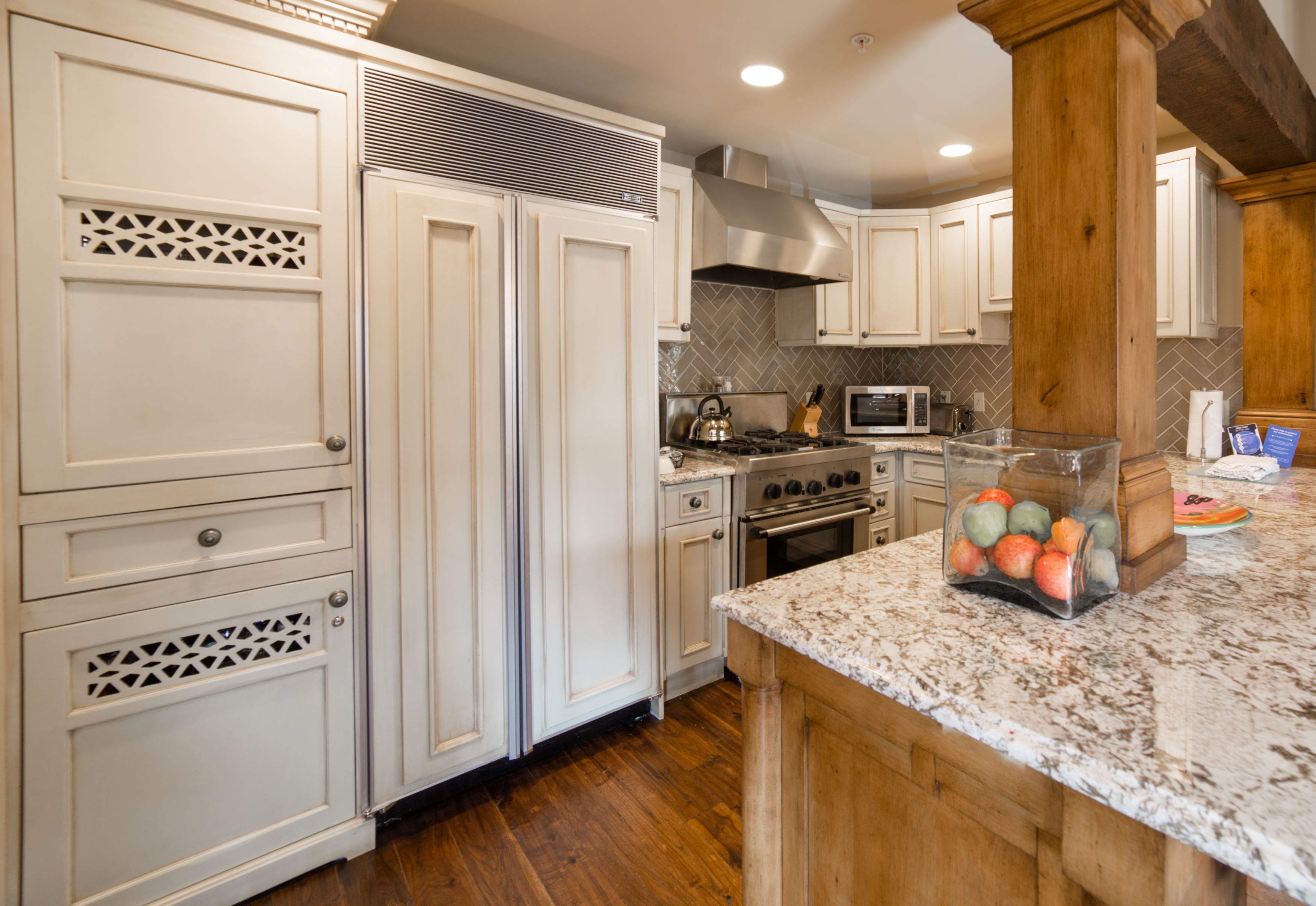 A kitchen with white cabinetry, a granite countertop, and a stainless steel range hood.