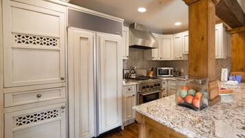 A kitchen with white cabinetry, a granite countertop, and a stainless steel range hood.