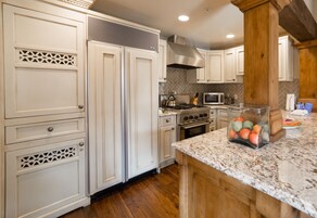 A kitchen with white cabinetry, a granite countertop, and a stainless steel range hood.