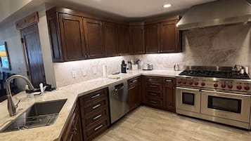 A modern kitchen with dark wooden cabinets, a stainless steel stove, and a built-in dishwasher.