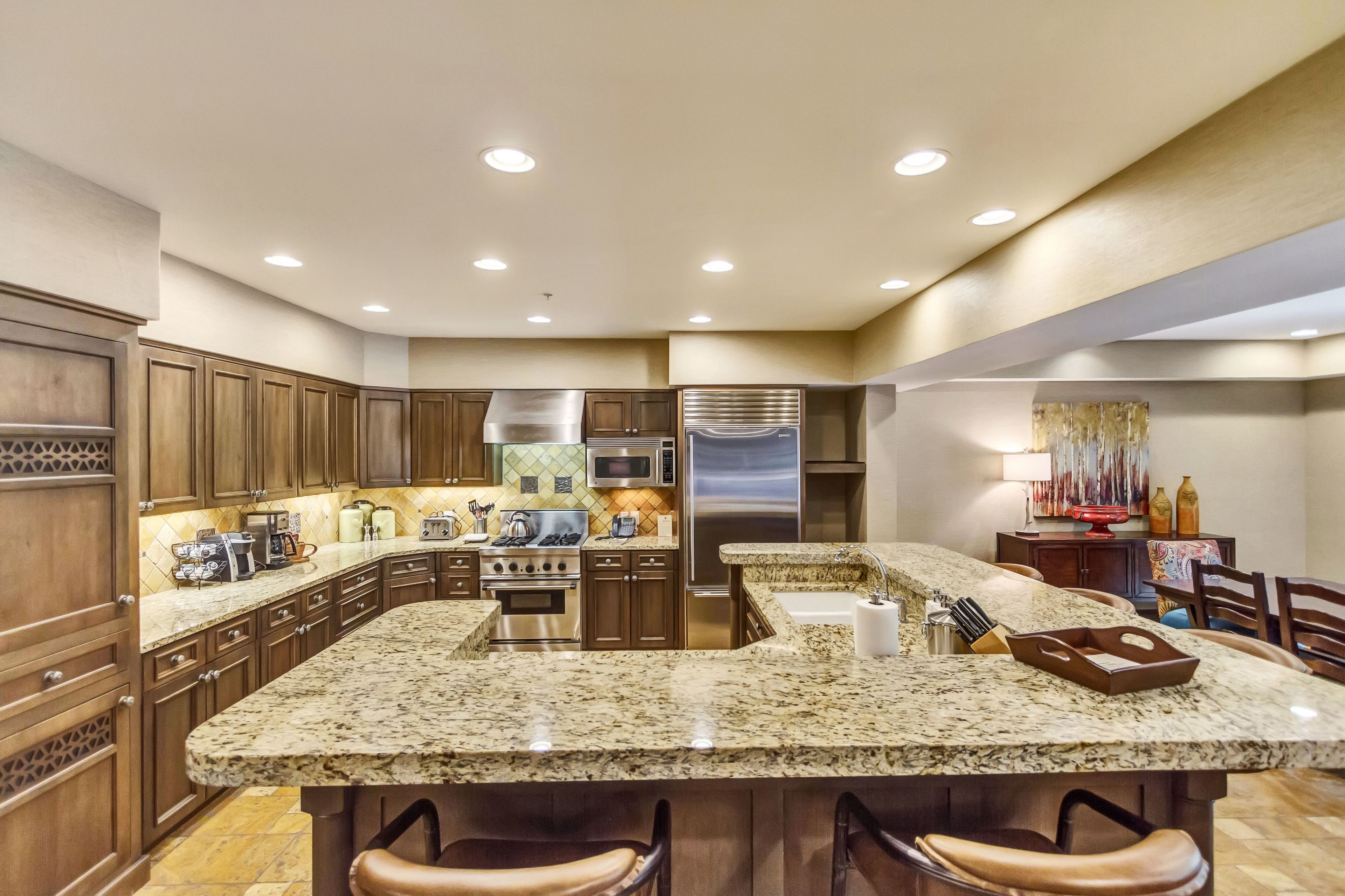Una cocina moderna con encimeras de granito, electrodomésticos de acero inoxidable y armarios de madera.