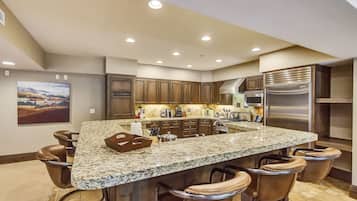 A kitchen with a large island, bar stools, wooden cabinets, and stainless steel appliances.