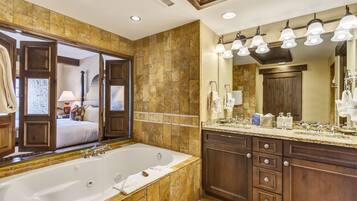 A spacious bathroom with a large bathtub, a vanity with a mirror, and a shower area.