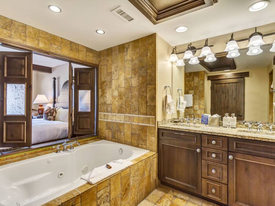 A spacious bathroom with a large bathtub, a vanity with a mirror, and a shower area.