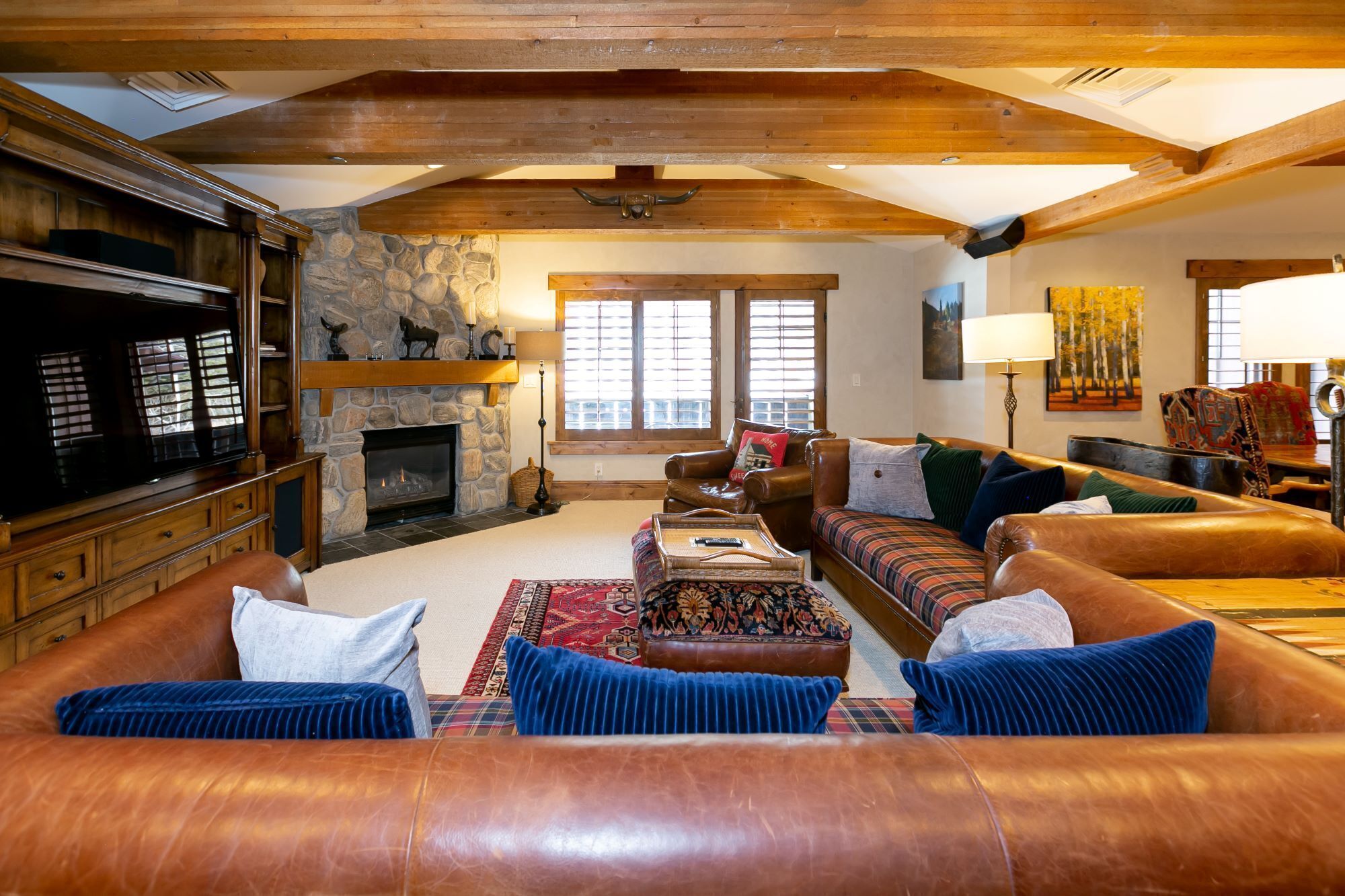A cozy living room with a stone fireplace, leather sofas, and a television.