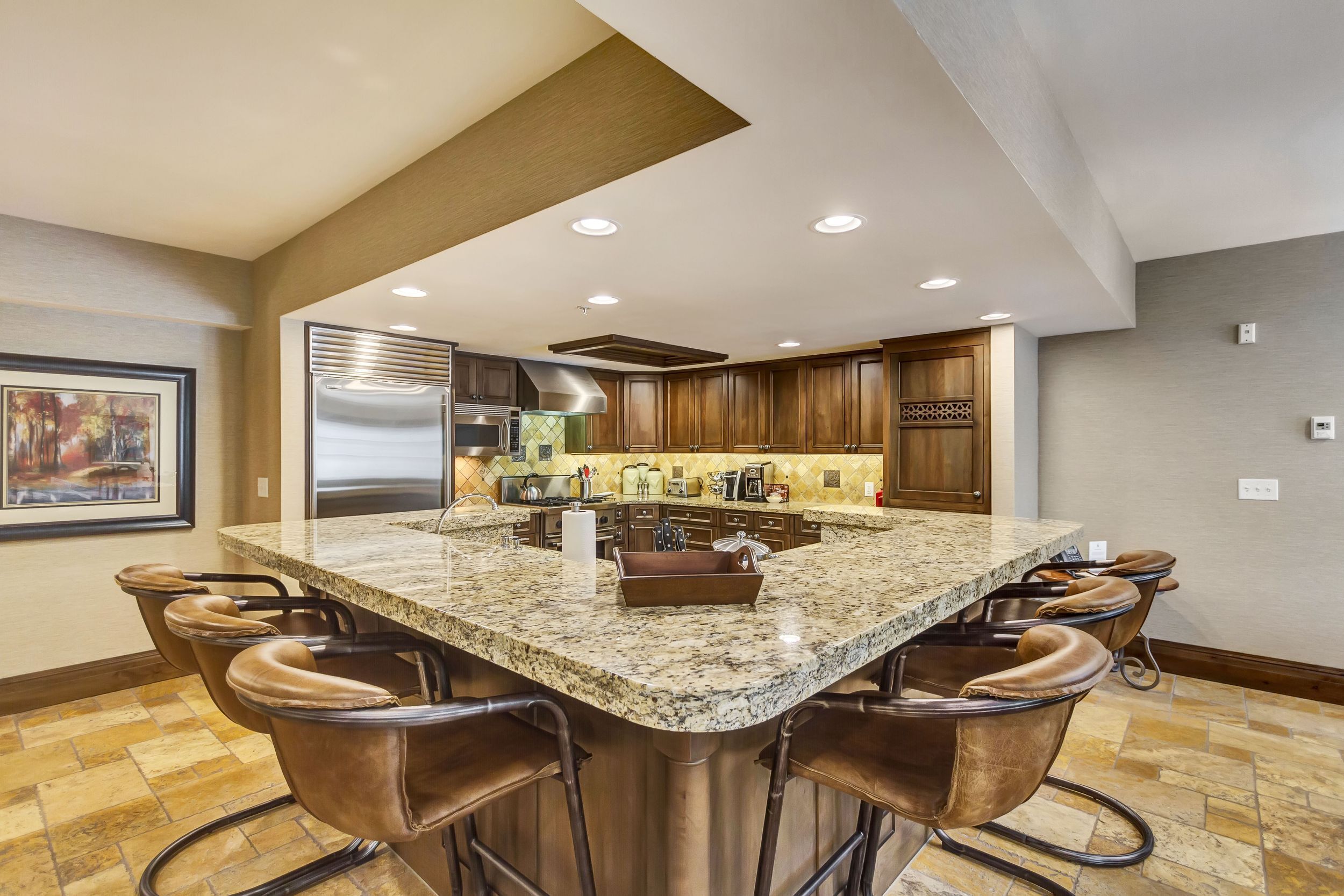 A modern kitchen with a large island, bar stools, and built-in appliances.