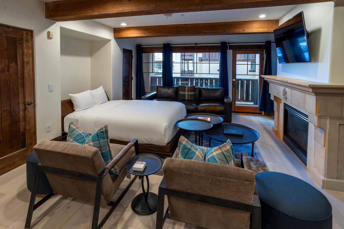 Ein Hotelzimmer mit einem großen Bett, einem Kamin, einem Fernseher und einem Balkon mit Blick.