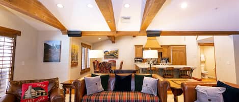 A cozy living room with a fireplace, leather sofas, and a dining area with wooden furniture.