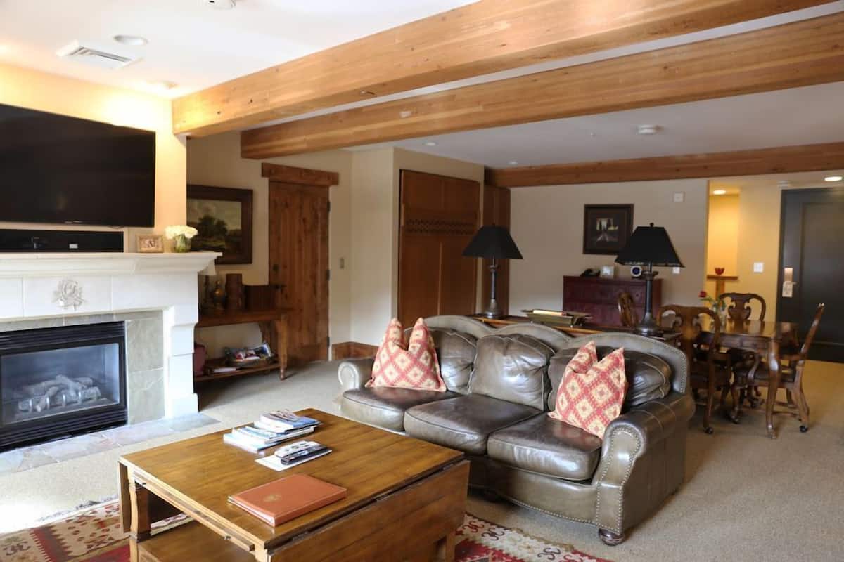 Ein Wohnzimmer mit Kamin, Ledersofa, Couchtisch aus Holz und einem Fernseher.