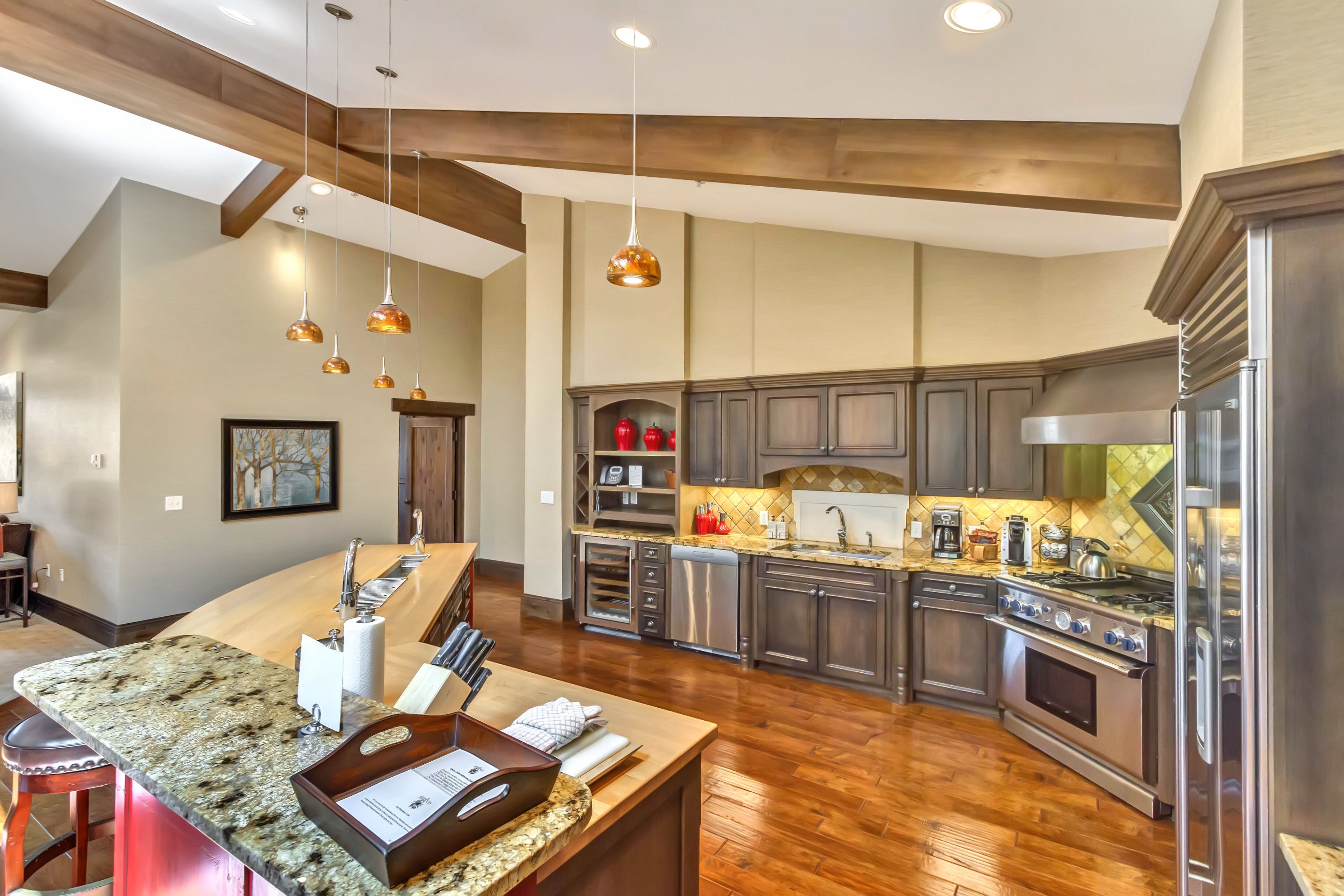 A spacious kitchen with granite countertops, stainless steel appliances, and wooden beams on the ceiling.