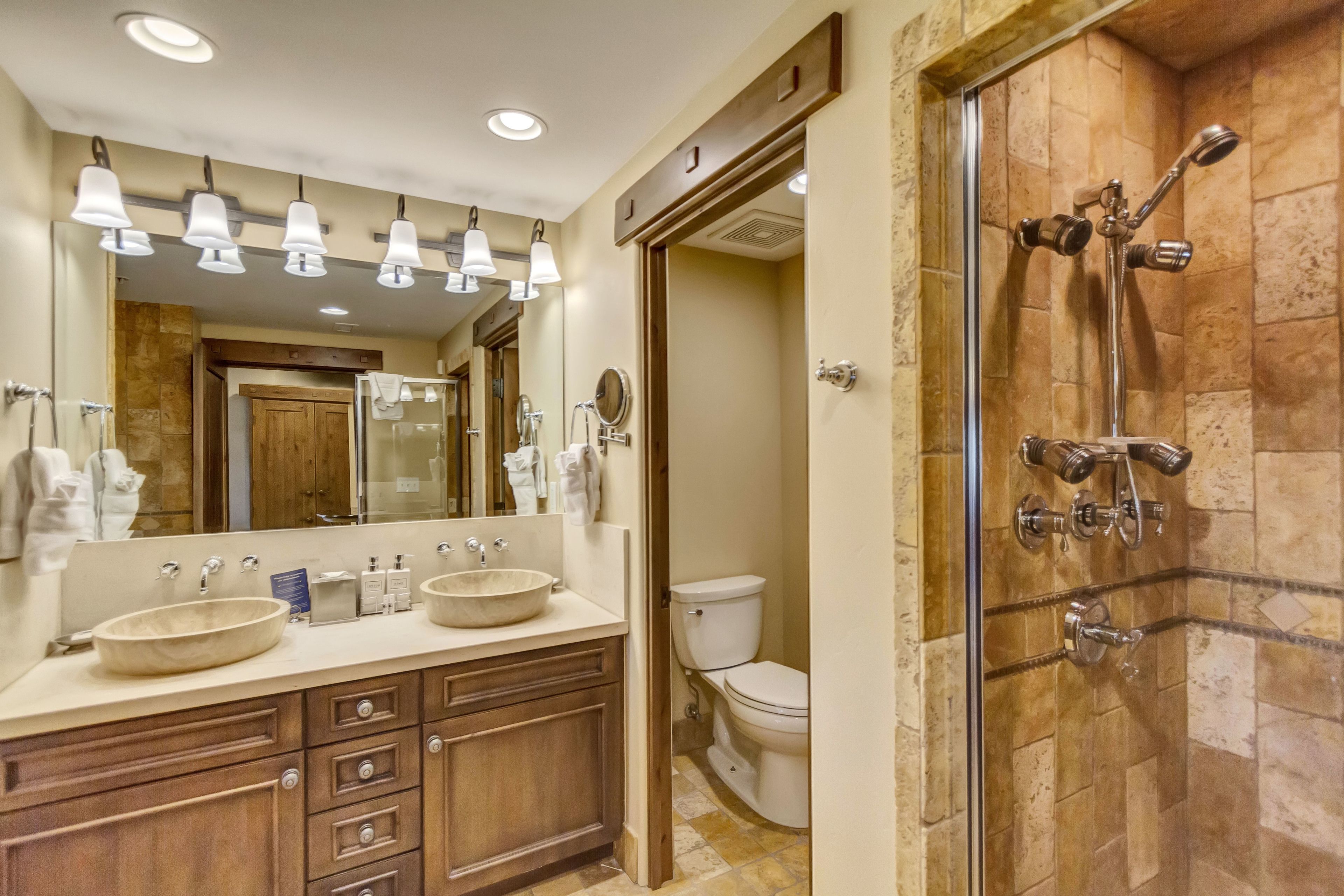 A bathroom with two sinks, a large mirror, and a shower with multiple heads.