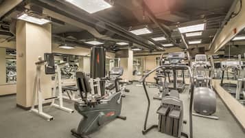 Un gimnasio con diversos equipos de ejercicio, incluyendo cintas de correr, elípticas y máquinas de pesas.