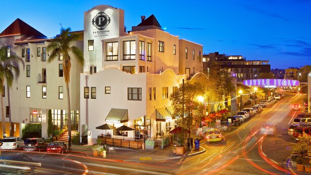 A hotel with a prominent 'P' logo, outdoor seating, and a busy street in the background. - La Pensione Hotel (San Diego)