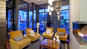 A modern lounge with large windows, comfortable seating, and a fireplace. - La Pensione Hotel (San Diego)
