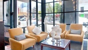 A modern interior with large windows, a central coffee table, and two armchairs. - La Pensione Hotel (San Diego)