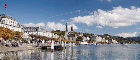 A waterfront cityscape with historic buildings, a church with two spires, and a calm river.