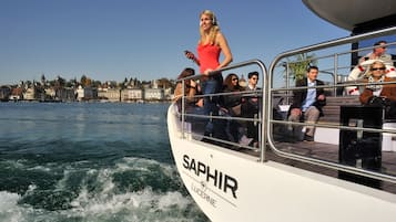 A boat with passengers, a clear view of the water, and a cityscape in the background.