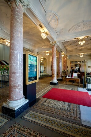 Experience the grandeur of our lobby, featuring an ornate chandelier, marble columns, and a traditional patterned carpet.