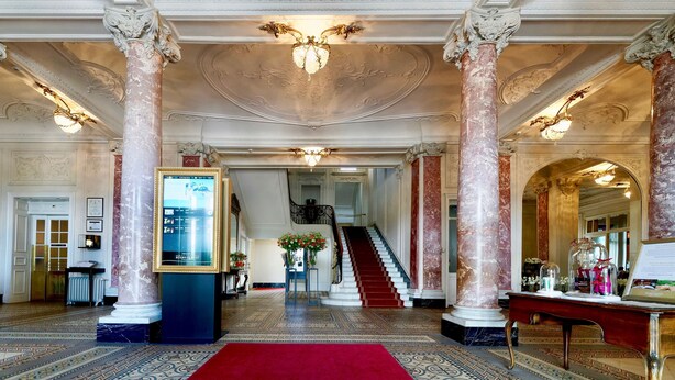 A grand lobby with ornate columns, a red carpet, and a staircase leading to upper floors. - Hotel Schweizerhof Luzern (Lucerne)