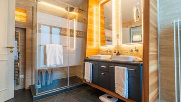 A modern bathroom with a glass shower enclosure, dual sinks, and a large mirror.