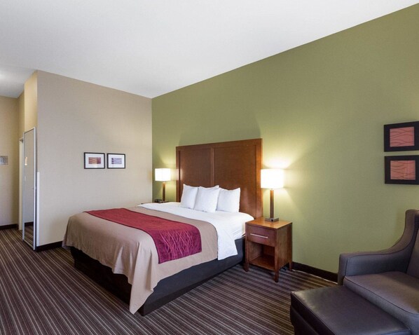 A hotel room with a bed, bedside tables, a chair, and a mirror.