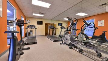 A gym with multiple exercise machines, including treadmills and stationary bikes, arranged in rows.