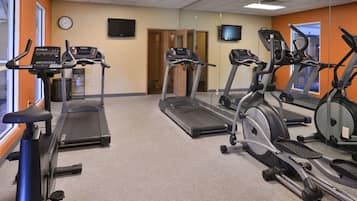 Une salle de sport équipée de tapis de course, de vélos d’appartement et d’une machine de musculation.