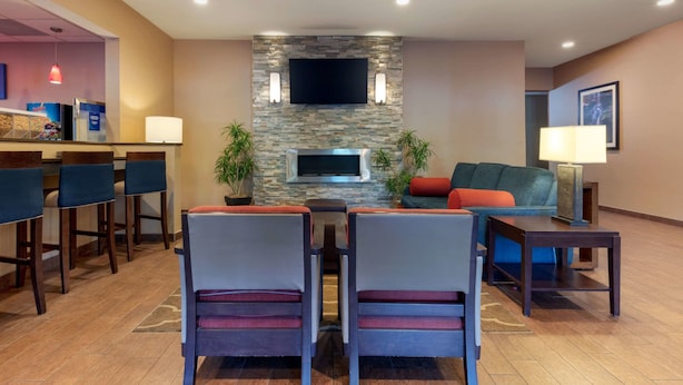 A modern hotel lobby with a stone fireplace, seating area, and a bar. - Comfort Inn & Suites Fayetteville - University Area (Fayetteville)