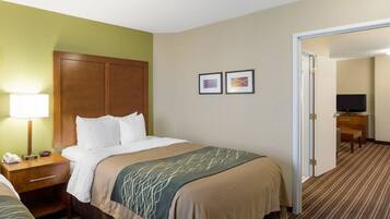 A hotel room with a bed, bedside table, lamp, and a television in the corner.