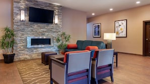 A modern living room with a stone wall, flat-screen TV, comfortable seating, and decorative plants. - Comfort Inn & Suites Fayetteville - University Area (Fayetteville)