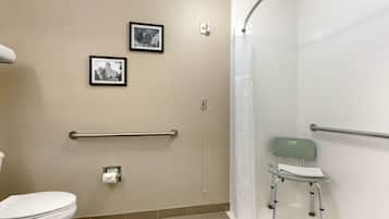 A bathroom with a toilet, two framed pictures on the wall, a handrail, a shower curtain, and a wheelchair.