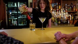 A bar setting with a bartender pouring a drink into a glass.