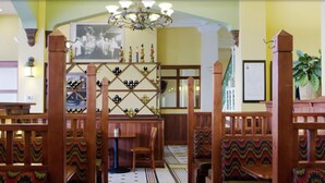 A restaurant with wooden booths, a chandelier, and a wall-mounted wine rack.