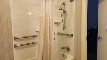 A bathroom with a bathtub, a shower with a handheld showerhead, and a towel rack.