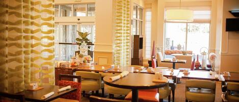 A hotel lobby with multiple seating areas, a reception desk, and a large window providing natural light.