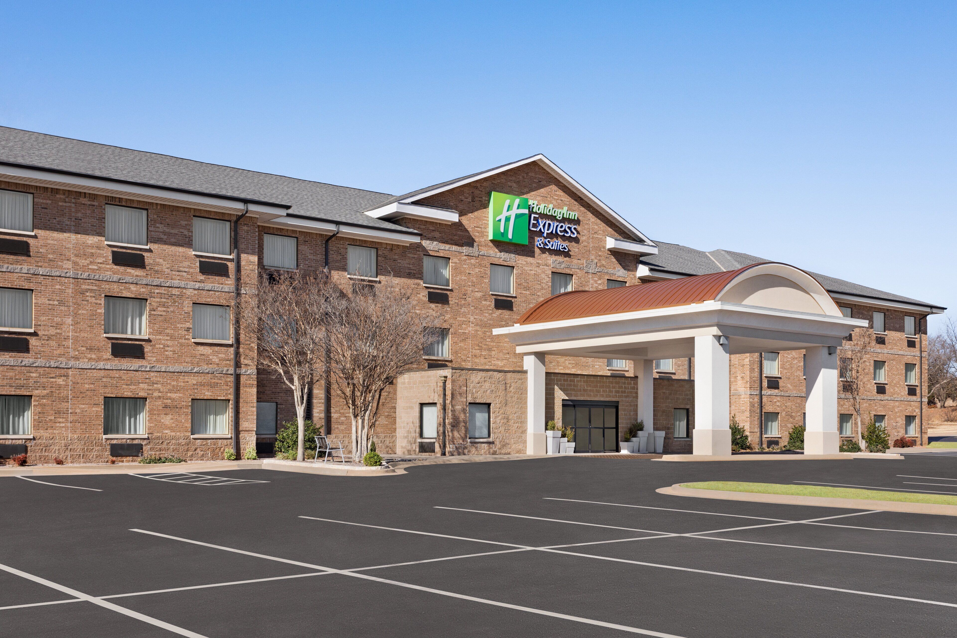 Un bâtiment de la chaîne Holiday Inn Express, avec une façade en briques, une entrée abritée et un parking.