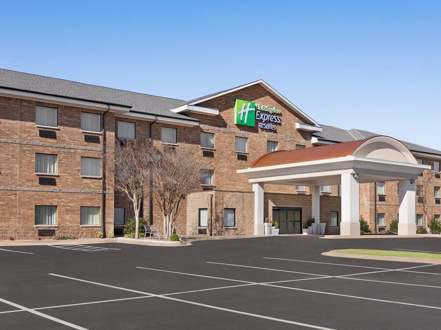Un edificio Holiday Inn Express con fachada de ladrillo, un acceso cubierto y un estacionamiento.