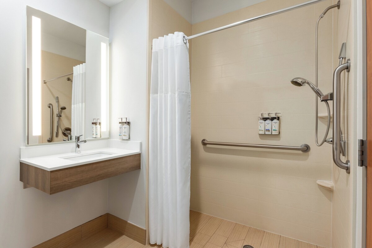 A modern bathroom with a shower, a sink, and a mirror.