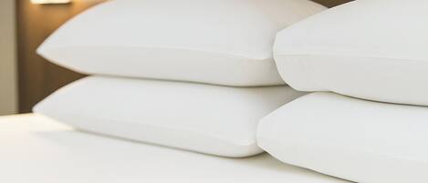 A bed with white pillows and a wooden headboard.