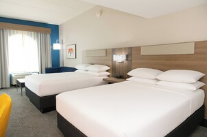 Quarto de hotel com duas camas, uma escrivaninha e uma cadeira.